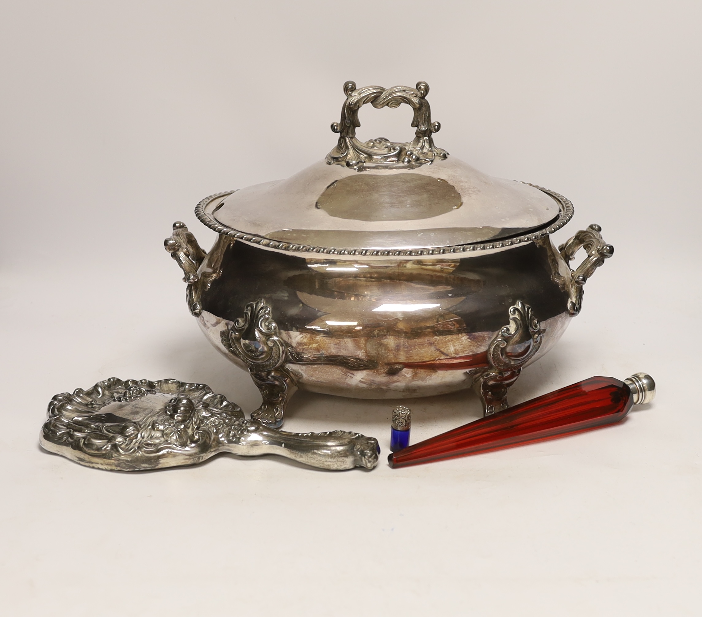 A Victorian red glass and sliver topped perfume bottle, 23cm long, a miniature blue glass silver topped bottle, together with a plated hand mirror and a tureen and cover
